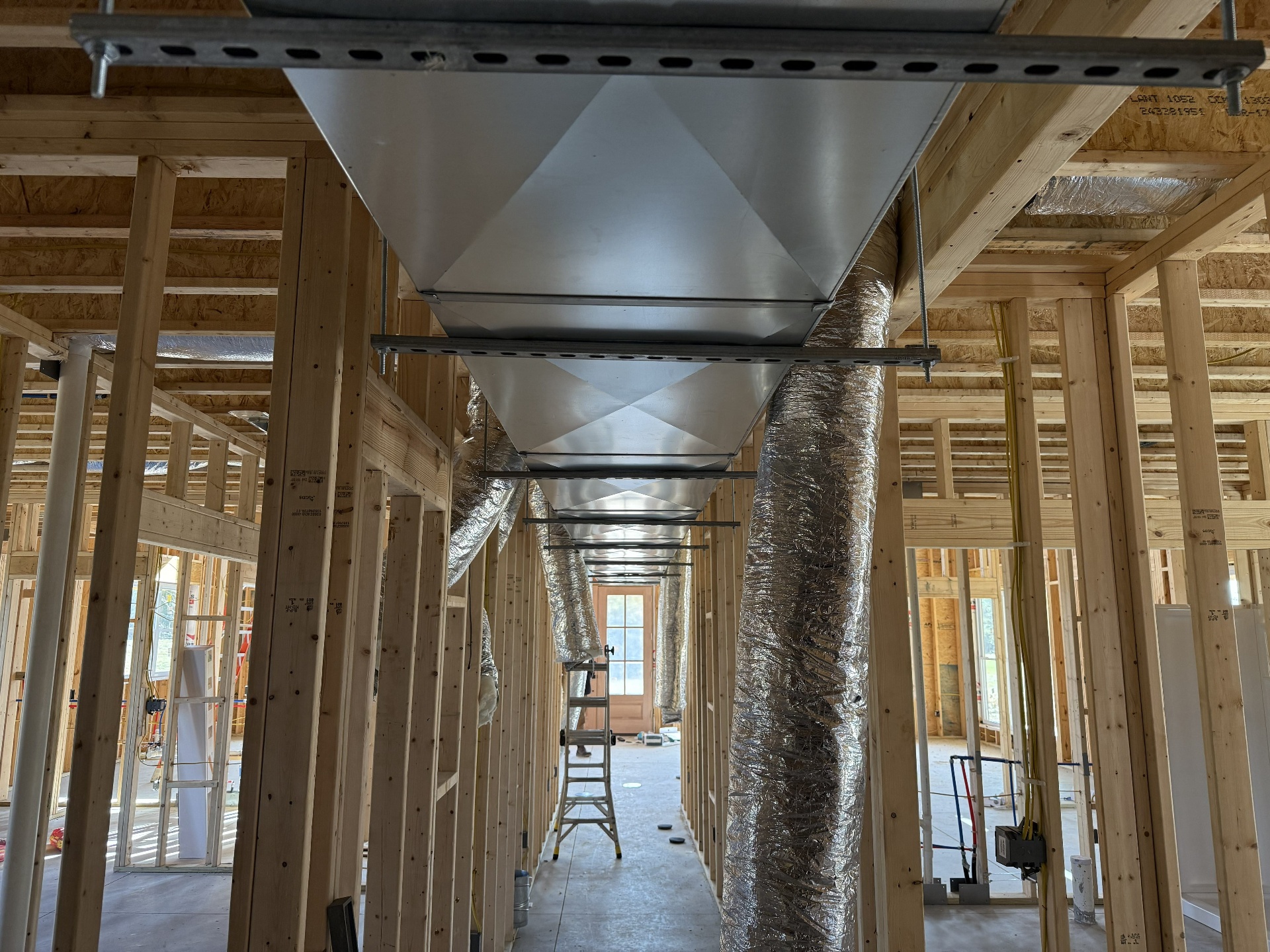 Main metal trunk duct installed through a framed home during HVAC rough-in