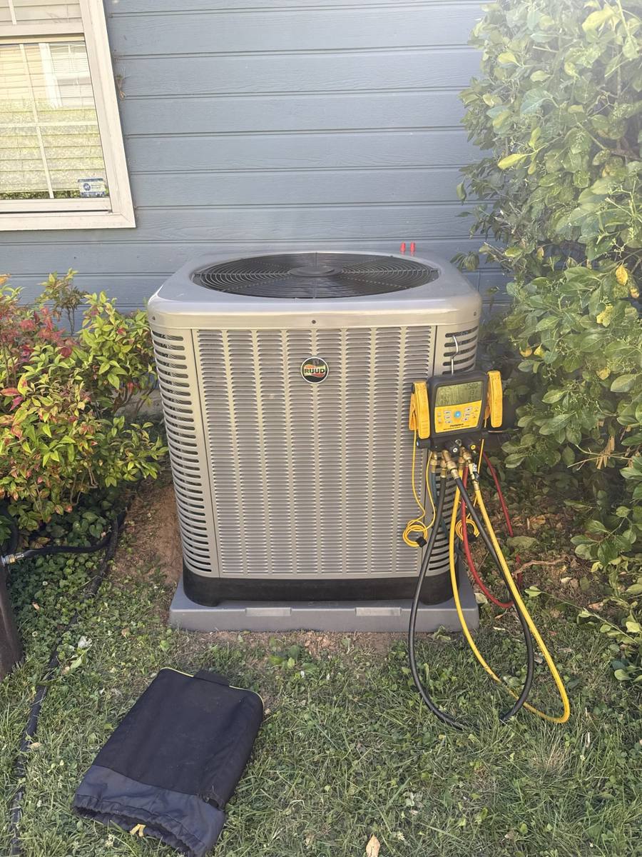 Ruud outdoor condenser being tested with digital HVAC gauges during a service visit