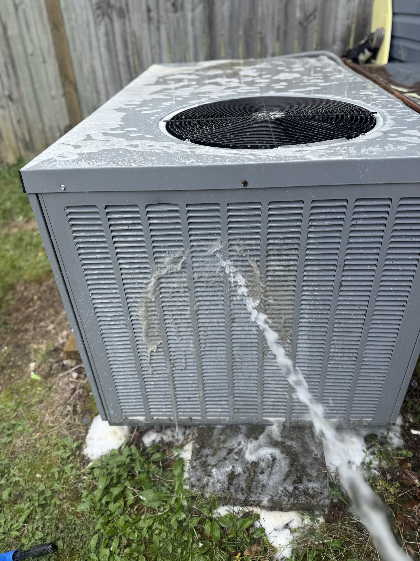Outdoor condenser coil being flushed during a Cranfield Services HVAC maintenance visit