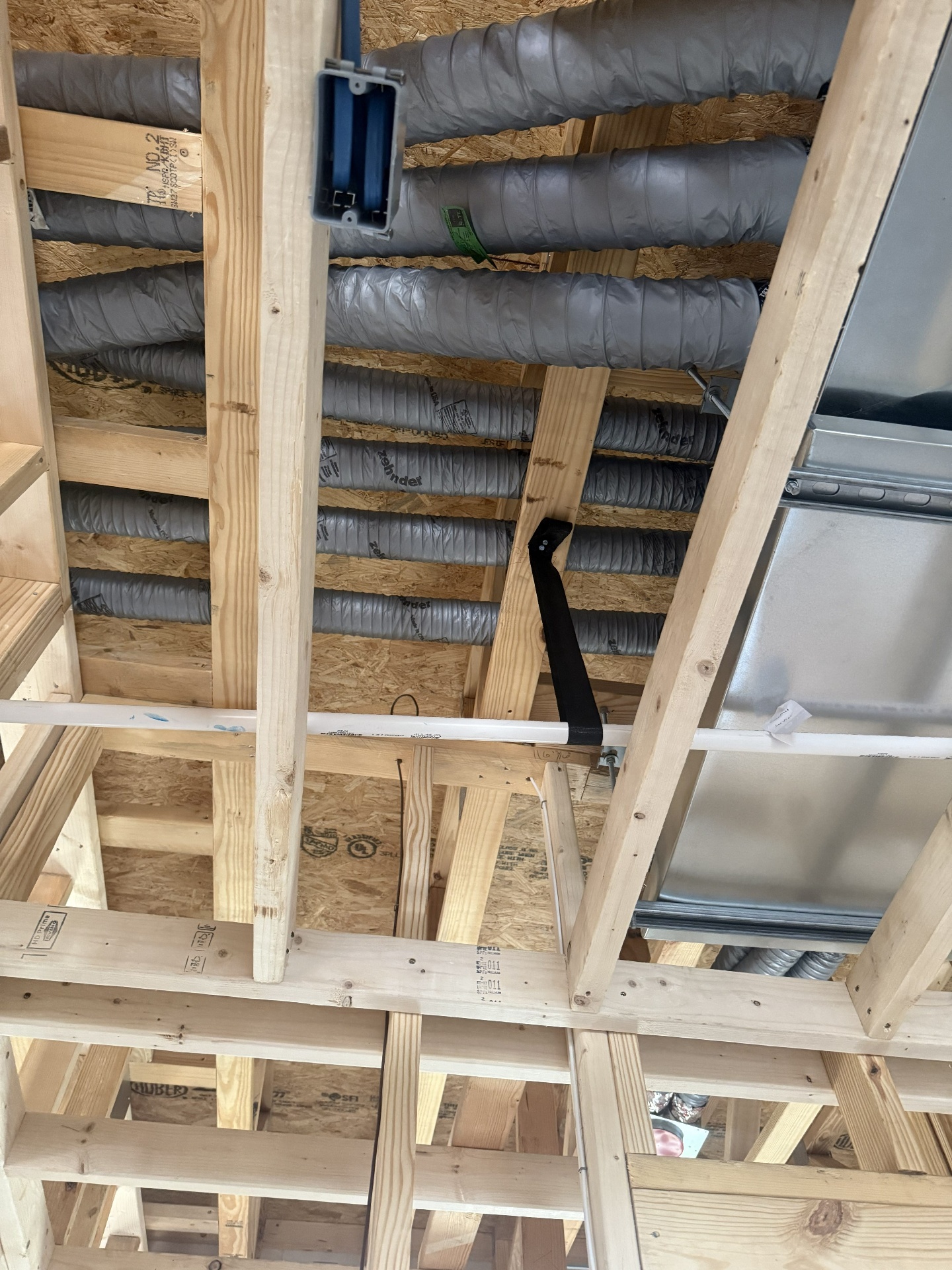 New branch ductwork installed neatly through open framing during a new construction HVAC project